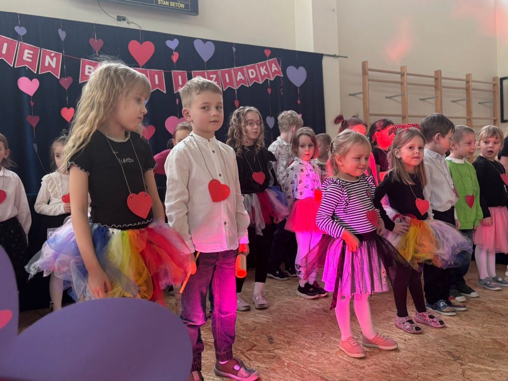 Dzieci stoją na scenie podczas występu z okazji Dnia Babci i Dziadka.