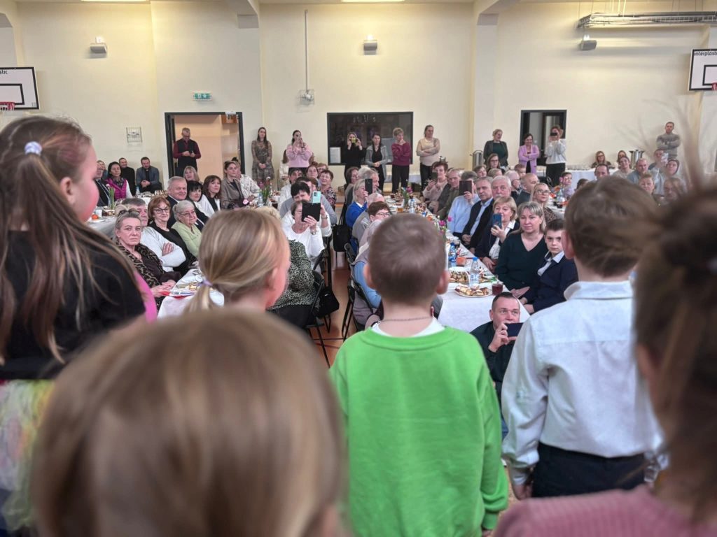 Dzieci występują przed publicznością zgromadzoną na uroczystości szkolnej.