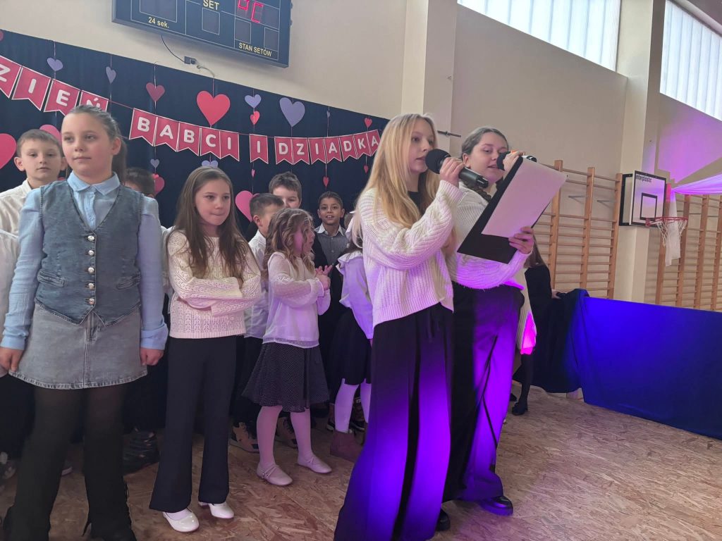 Uczniowie występują na scenie w części wokalnej programu artystycznego.