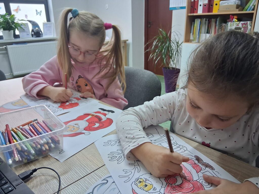 Dziewczynki kolorują obrazki św. Mikołaja z reniferami